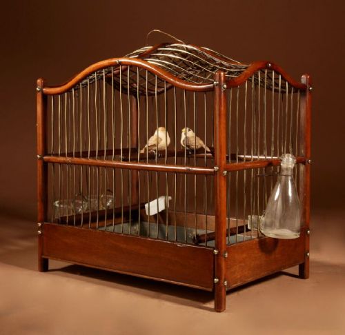 An Anglo-Dutch mahogany and brass birdcage featuring an arched wire dome roof, slide-out drawer tray, wooden perches, and accompanying glass vessels. View VI