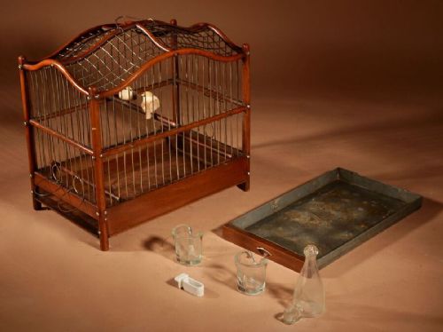 An Anglo-Dutch mahogany and brass birdcage featuring an arched wire dome roof, slide-out drawer tray, wooden perches, and accompanying glass vessels. View XI