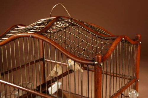 An Anglo-Dutch mahogany and brass birdcage featuring an arched wire dome roof, slide-out drawer tray, wooden perches, and accompanying glass vessels. View XII