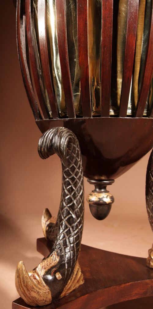 A French Empire mahogany slatted wine cooler featuring a brass liner and supported by three carved ebonised dolphin legs on a triform base with paw feet. View VII