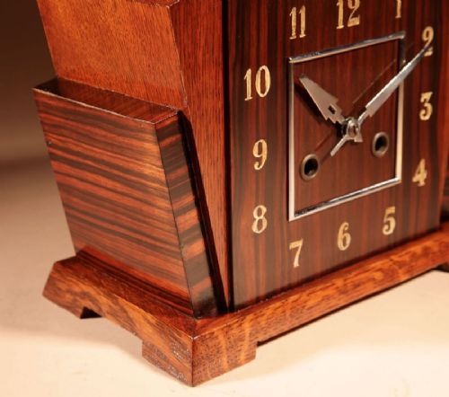 An Art Deco Amsterdam School mantel clock featuring geometric oak and dark Macassar ebony wood veneer with brass numerals and angular hands. View IX
