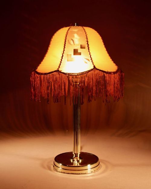 An Art Deco brass table lamp with a reeded column base and a tan stitched leather shade featuring geometric cut-outs and fringe trim. View III