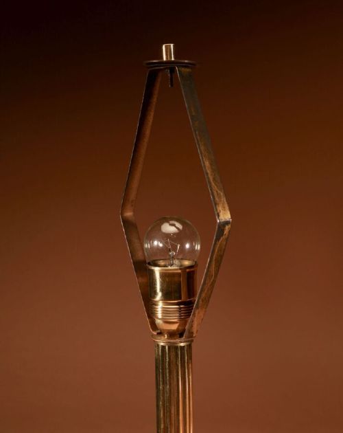 An Art Deco brass table lamp with a reeded column base and a tan stitched leather shade featuring geometric cut-outs and fringe trim. View VI