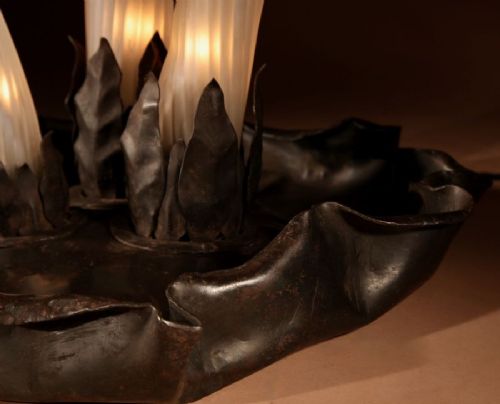 A triple mushroom table lamp featuring three illuminated white glass stems topped with red patterned glass caps set into a dark wrought iron base. View V