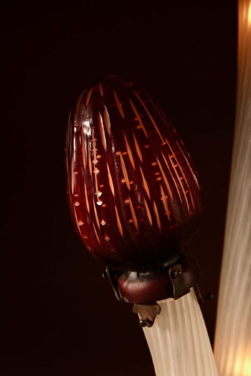 A triple mushroom table lamp featuring three illuminated white glass stems topped with red patterned glass caps set into a dark wrought iron base. View VI