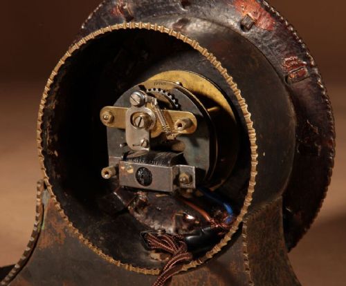 A circular hand-hammered patinated brass electric clock on a flared base with rectangular brass hour markers. View VI