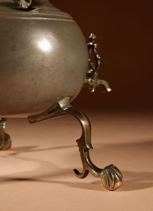 An 18th-century Dutch pewter kraantjeskan coffee urn featuring a bronze spigot tap, curved side handles, and three cabriole feet. View VII