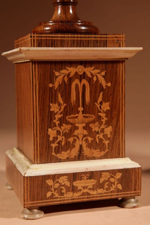A French Louis Philippe portico mantel clock set featuring floral wood inlay, architectural columns, a gilt metal pendulum, and two matching urn side pieces on decorative pedestals. View X