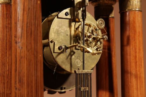 A French Louis Philippe portico mantel clock set featuring floral wood inlay, architectural columns, a gilt metal pendulum, and two matching urn side pieces on decorative pedestals. View XIV