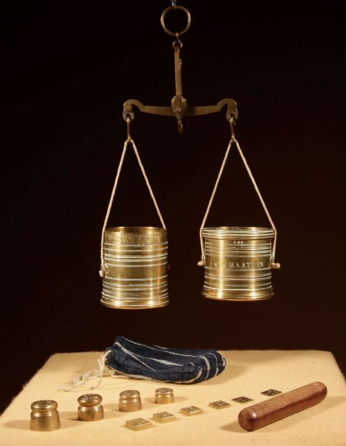 fig 1. An 1846 Dutch brass bushel balance set featuring a balance beam, two cylindrical brass measuring buckets, calibrated brass weights, a wooden striker, and a striped fabric pouch.
