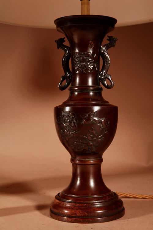 fig 1. A matching pair of dark patinated bronze vase-shaped table lamps with dragon handles and pleated cream lampshades.
