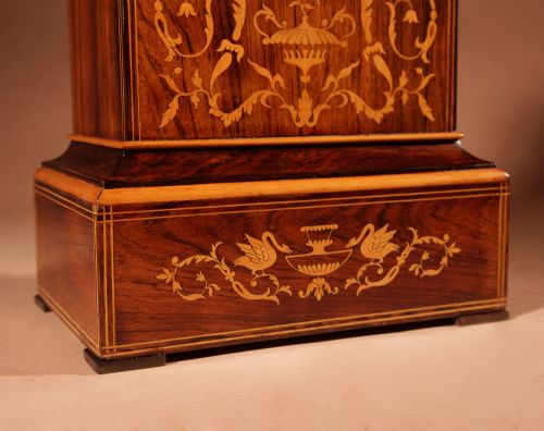 fig 1. A rectangular Charles X dark rosewood mantel clock featuring intricate floral marquetry inlay, a circular silvered dial with Roman numerals, and a cast brass carrying handle on top.