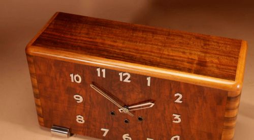 fig 1. A horizontal rectangular Art Deco walnut mantel clock with applied chrome Arabic numerals, chrome hands, and polished metal bracket feet.