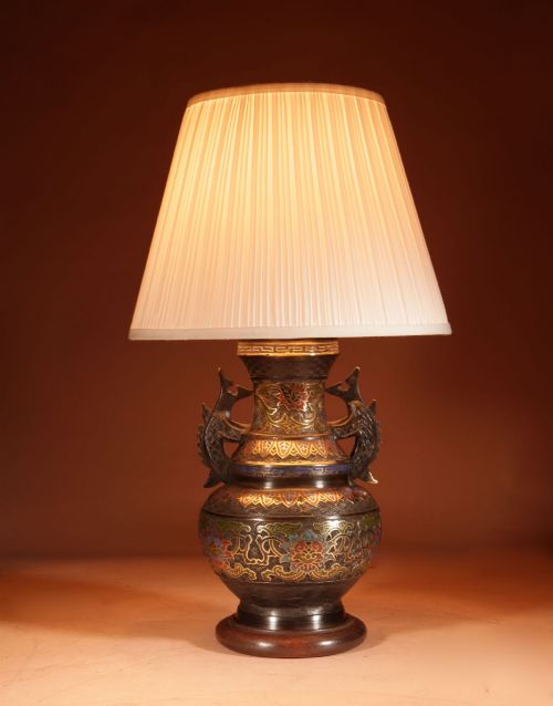 fig 1. A Japanese champleve bronze vase-form table lamp featuring cast dragon handles, colourful geometric enamel inlay, and a cream pleated shade.