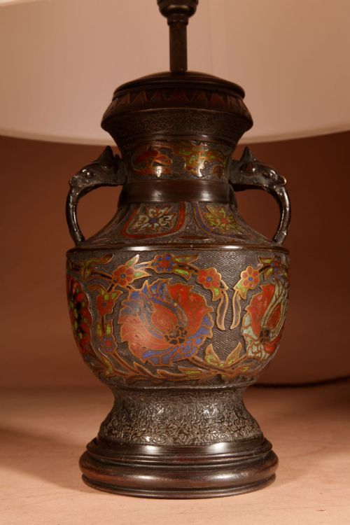 fig 1. A Japanese champleve bronze urn formatted as a table lamp with polychrome enamel floral patterns, sculpted handles, and a cream pleated shade.