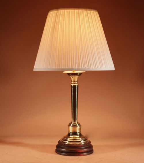 fig 1. A polished brass column table lamp featuring a turned hardwood base and a cream pleated fabric lampshade.