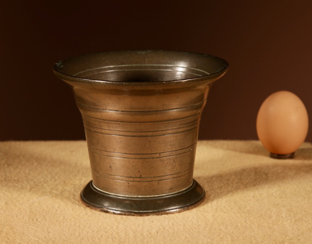 A small antique Dutch cast bronze mortar featuring a flared rim, horizontal turned ring bands around the body, and a dark aged patina.