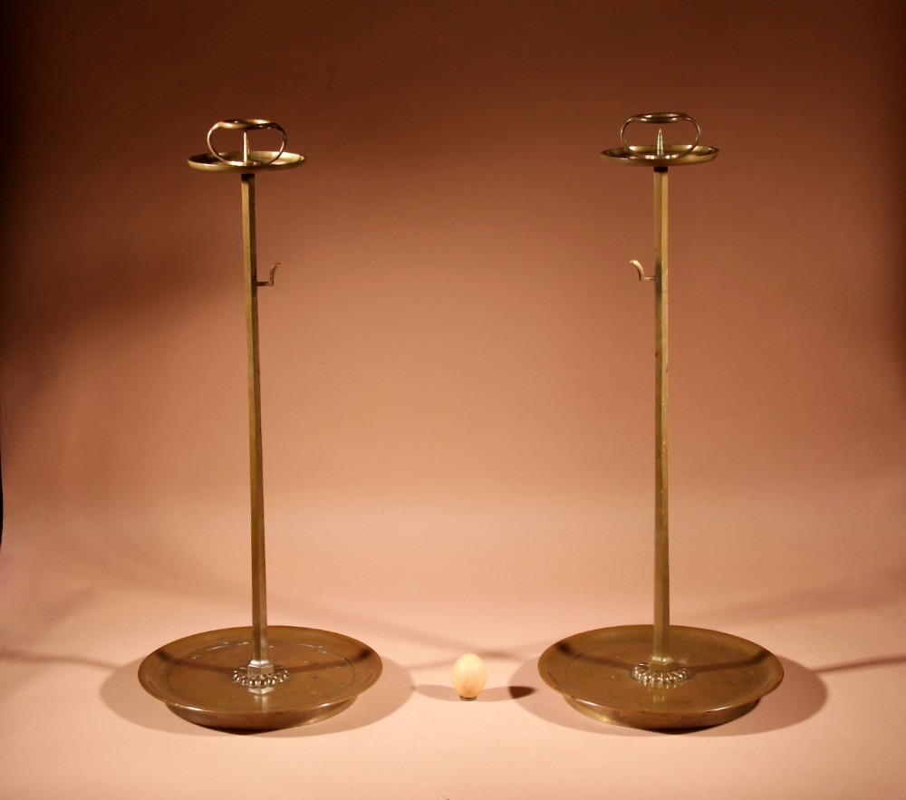 A pair of tall Japanese bronze pricket candlesticks featuring wide circular base drip trays, slender stems with side hooks, and upper pricket pans with arched handles.