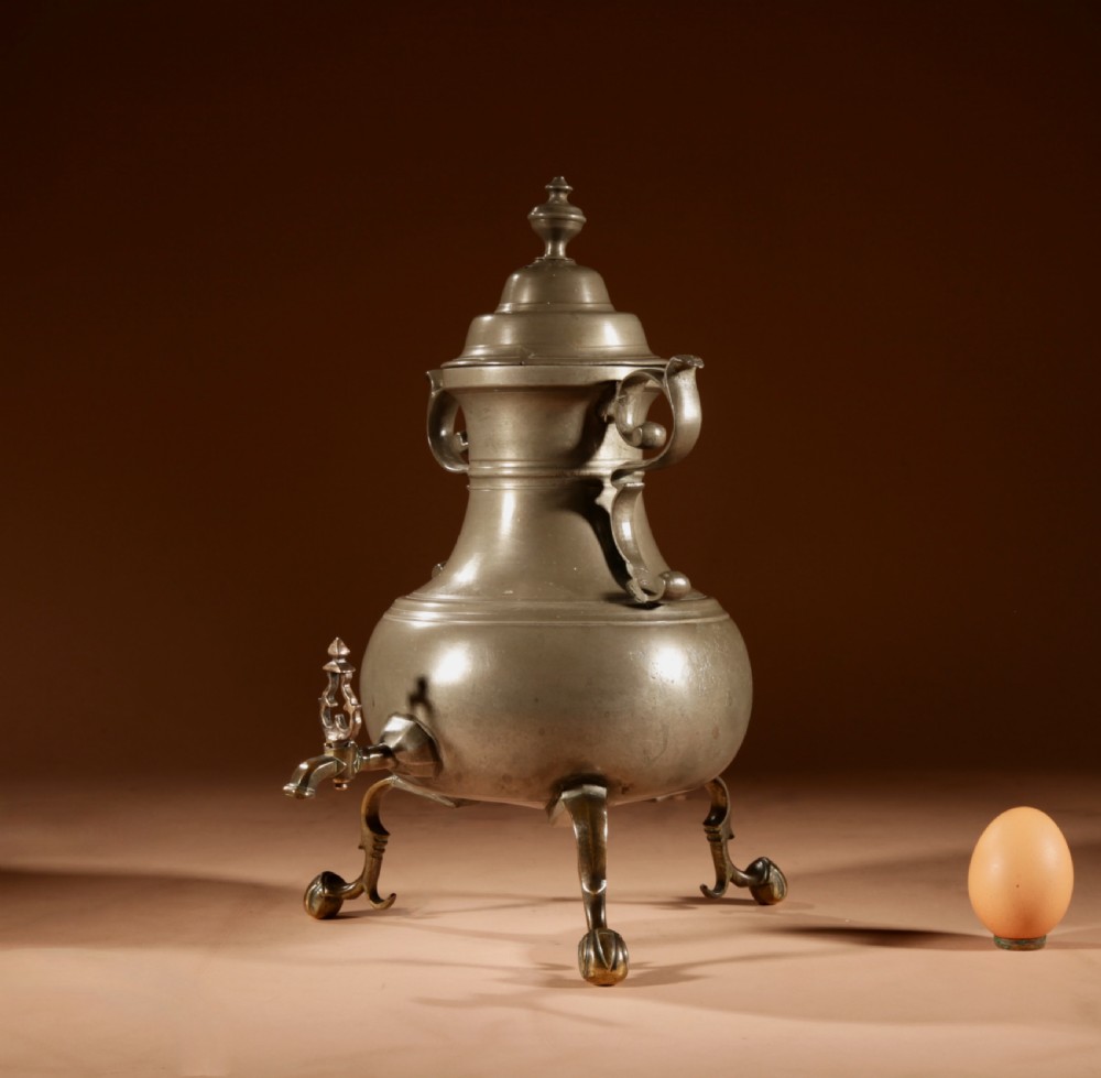 An 18th-century Dutch pewter coffee urn featuring a bulbous body, brass spigot, twin handles, and tripod bronze legs.