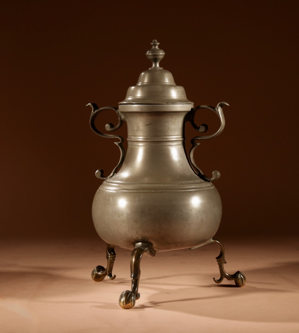 An 18th-century Dutch pewter coffee urn featuring a bulbous body, brass spigot, twin handles, and tripod bronze legs. View V