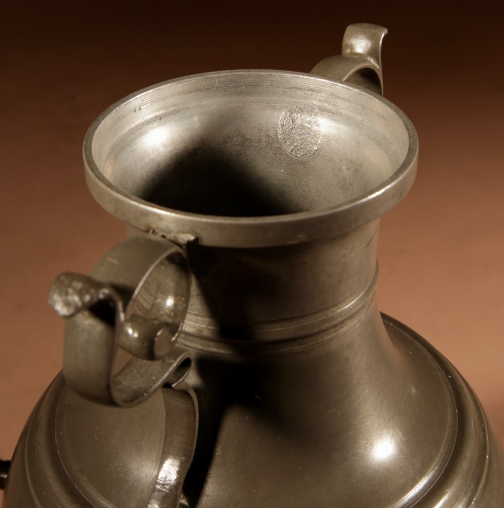 An 18th-century Dutch pewter coffee urn featuring a bulbous body, brass spigot, twin handles, and tripod bronze legs. View XIV