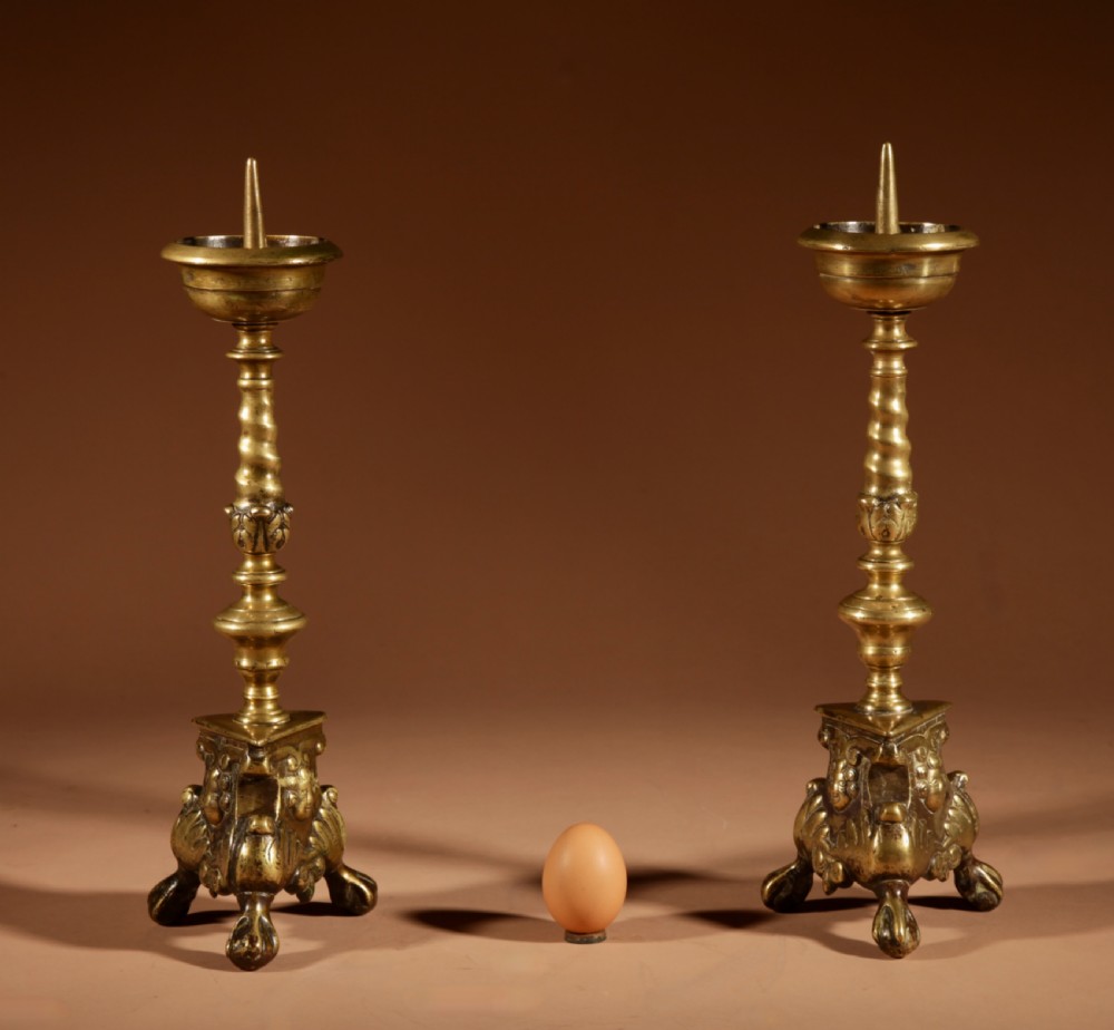 A pair of 17th-century Flemish turned brass pricket candlesticks with spiral shafts and ornate tripod claw feet.