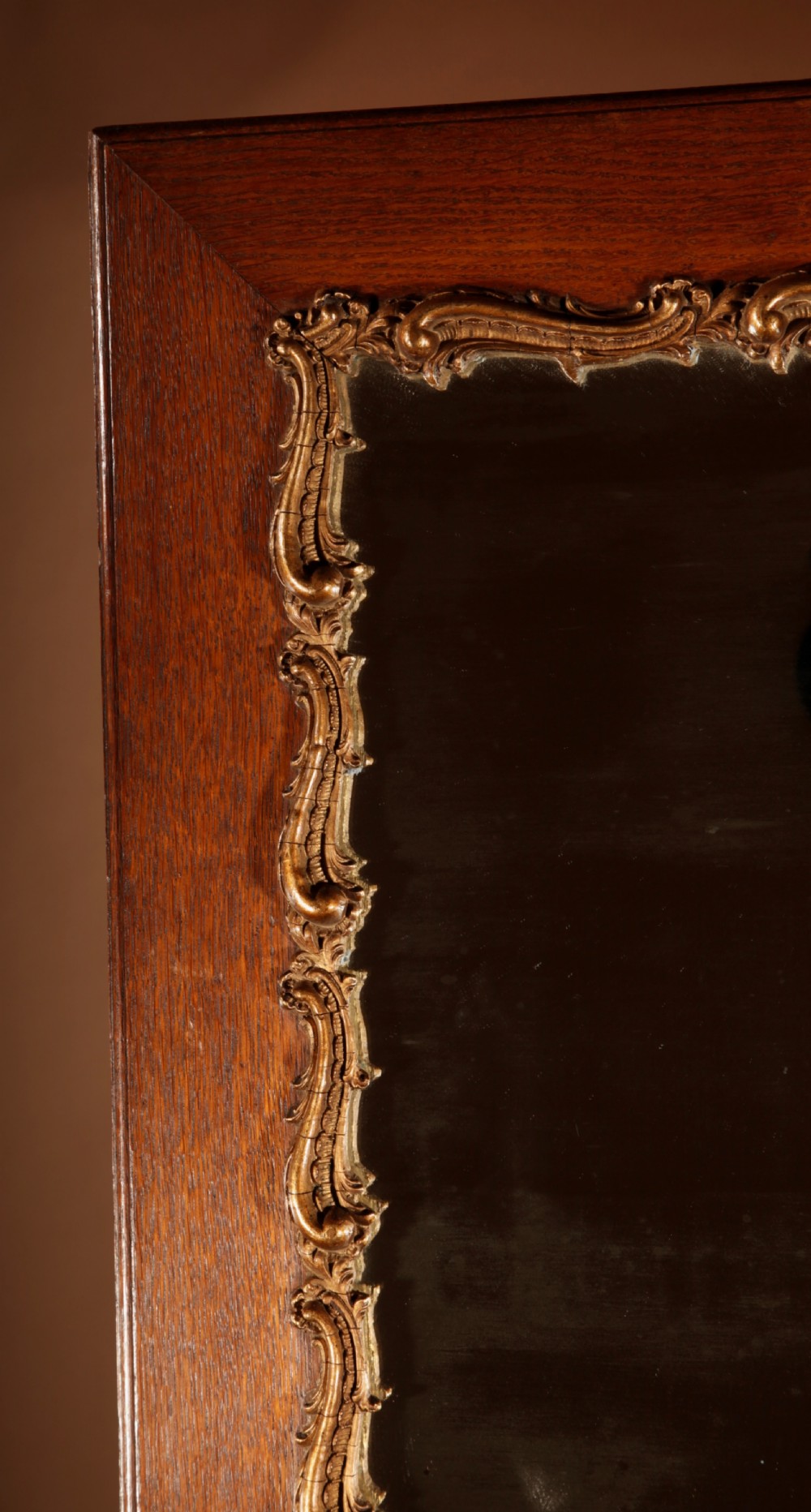 A rectangular oak wall mirror featuring a flat timber frame and a gilded gesso Rococo border surrounding the central mirror glass. View III