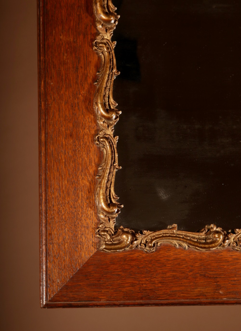 A rectangular oak wall mirror featuring a flat timber frame and a gilded gesso Rococo border surrounding the central mirror glass. View IV