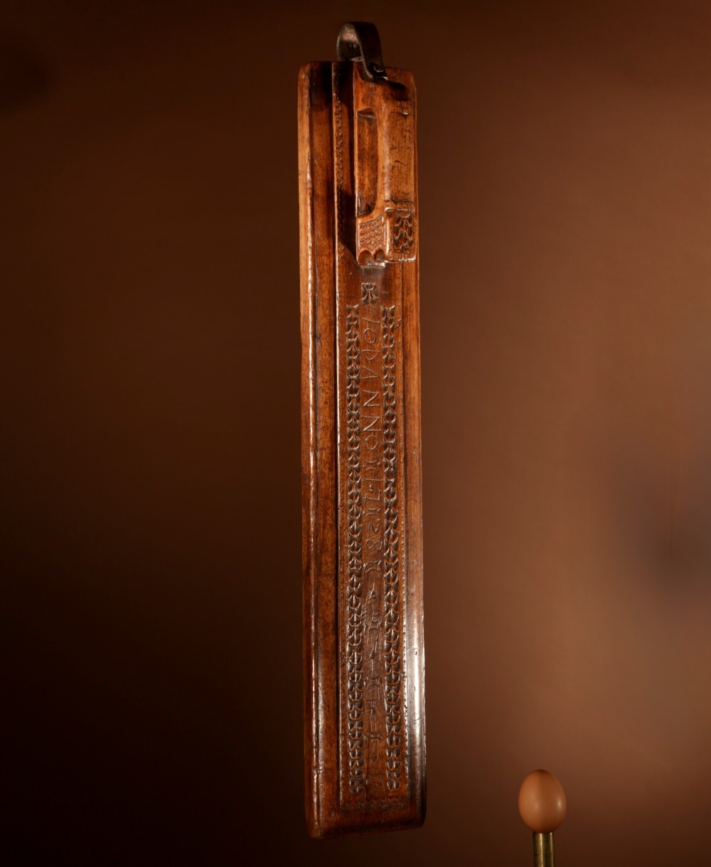 A hand-carved 18th-century Norwegian wooden mangle board with geometric chip carving, dated 1728, featuring a raised carved handle at one end.