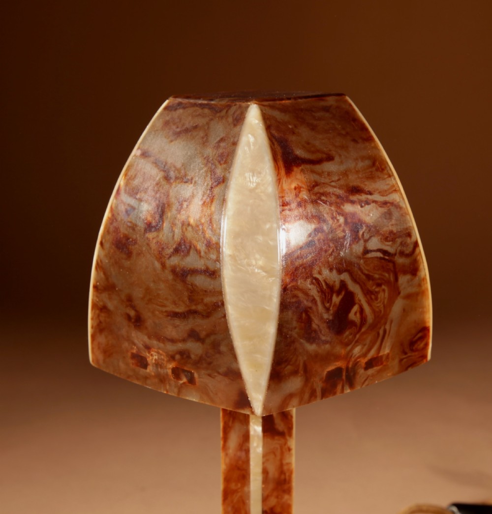 A small Art Deco table lamp made from marbled amber brown and cream celluloid with a faceted geometric shade. View V