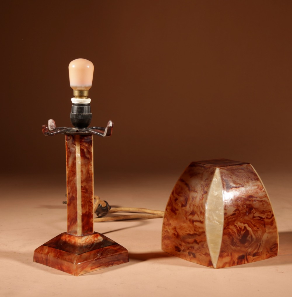 A small Art Deco table lamp made from marbled amber brown and cream celluloid with a faceted geometric shade. View VI