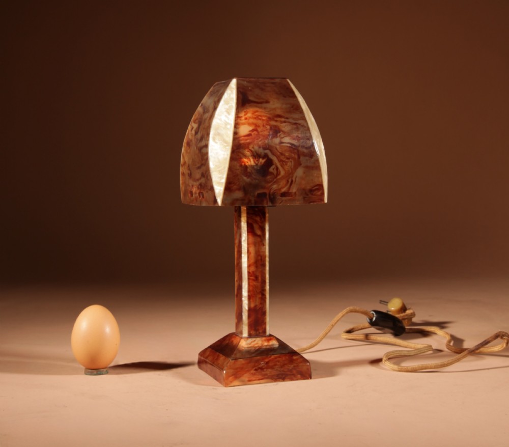 A small Art Deco table lamp made from marbled amber brown and cream celluloid with a faceted geometric shade. View VII