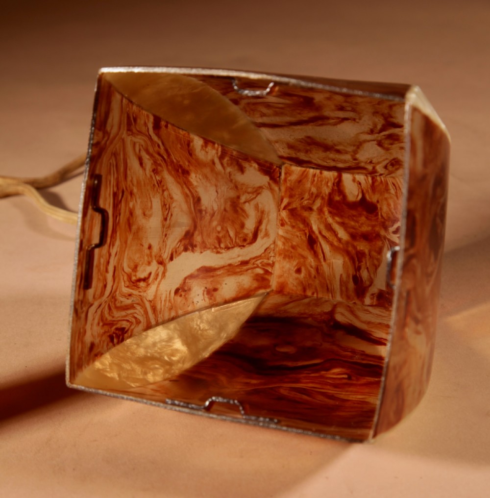 A small Art Deco table lamp made from marbled amber brown and cream celluloid with a faceted geometric shade. View IX