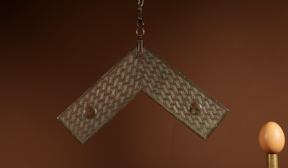 A chevron-shaped cast bronze musical chime featuring geometric relief patterns and a top suspension loop. View III