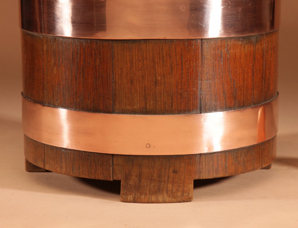A cylindrical dark oak planter constructed with vertical timber staves, bound by three horizontal copper bands, and supported by small wooden feet. View II