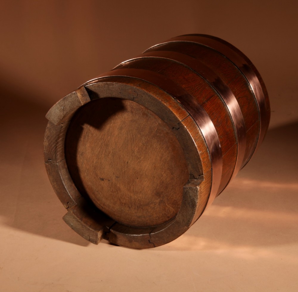 A cylindrical dark oak planter constructed with vertical timber staves, bound by three horizontal copper bands, and supported by small wooden feet. View VIII
