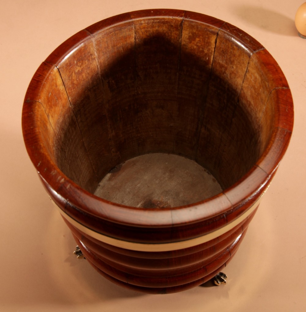 A coopered mahogany circular planter featuring polished brass banding and small brass feet. View V