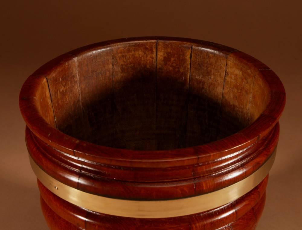 A coopered mahogany circular planter featuring polished brass banding and small brass feet. View VI