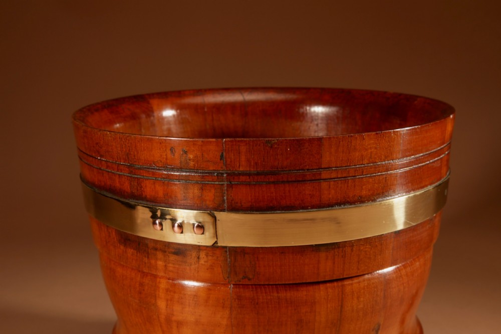 A turned teak planter featuring brass binding bands around the upper rim and base. View IV