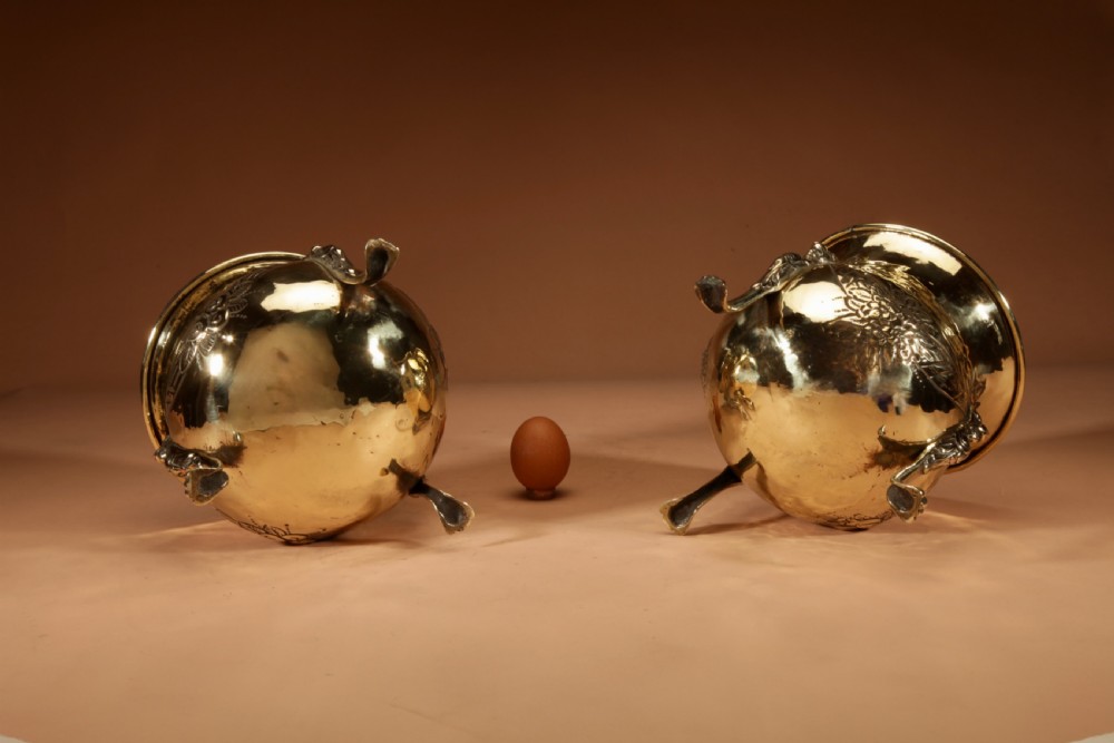 A pair of polished brass jardinieres featuring embossed floral swags and resting on tripod lion paw feet. View VIII