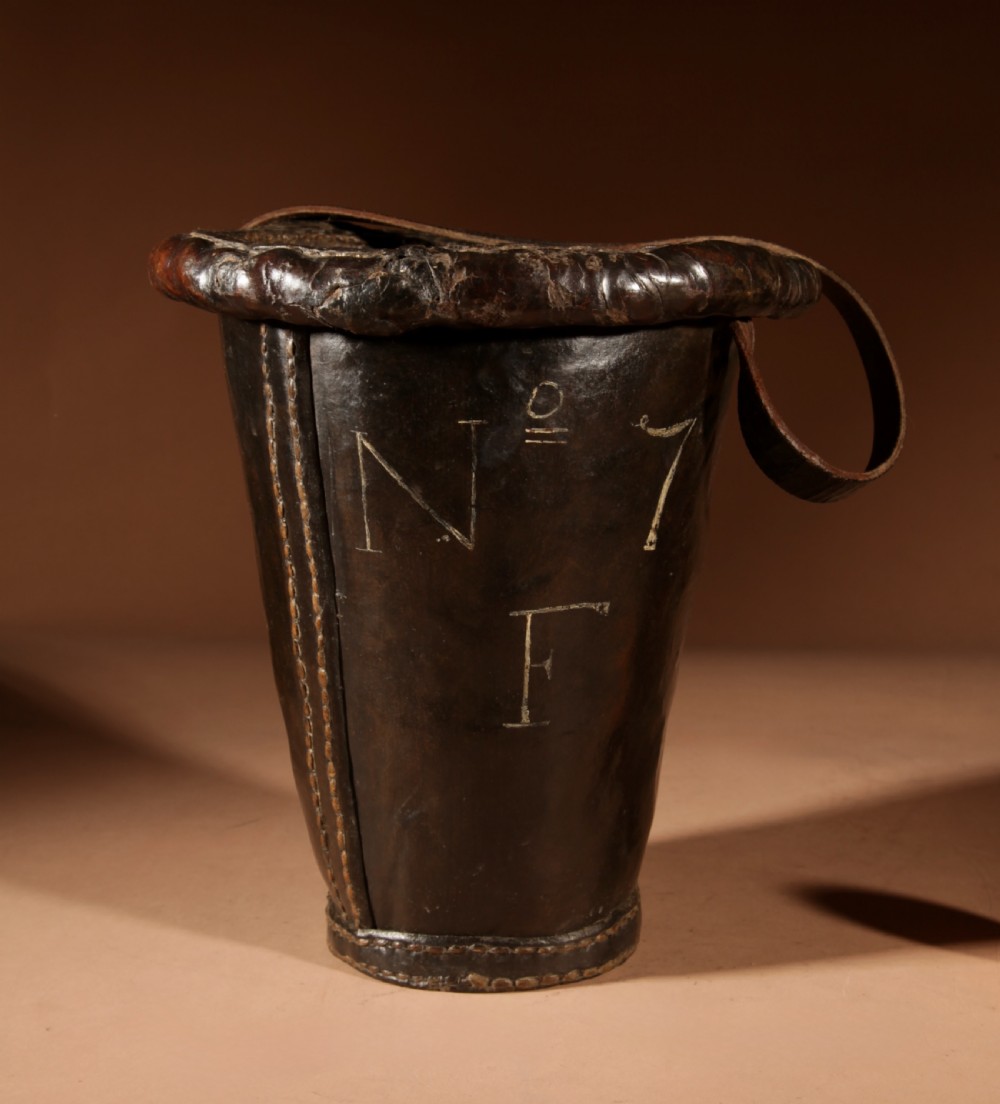An 18th-century dark brown leather fire bucket featuring a tall stitched leather handle, a thick rolled rim, and hand-painted cream lettering reading BRESYL ANNO 1776. View VIII