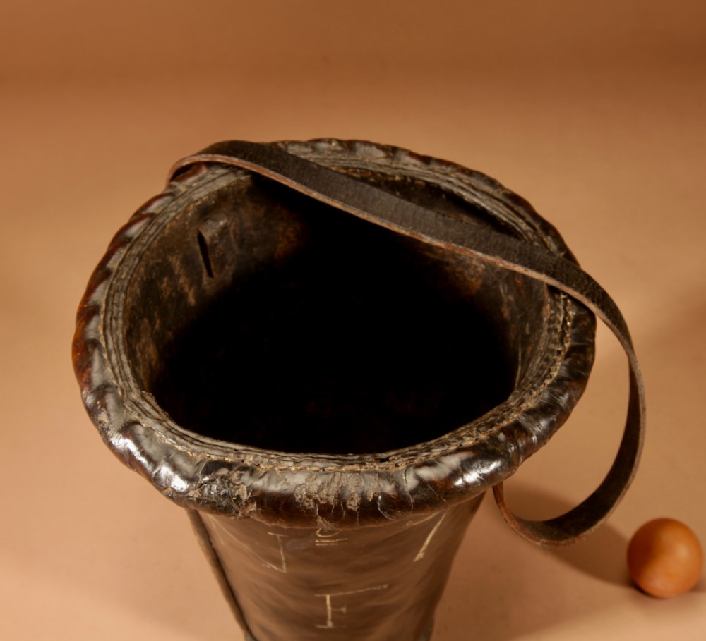 An 18th-century dark brown leather fire bucket featuring a tall stitched leather handle, a thick rolled rim, and hand-painted cream lettering reading BRESYL ANNO 1776. View IX