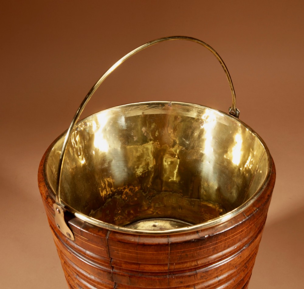 A tapered, coopered walnut bucket featuring horizontal ribbed bands, a fitted brass liner, and a brass swing handle. View III
