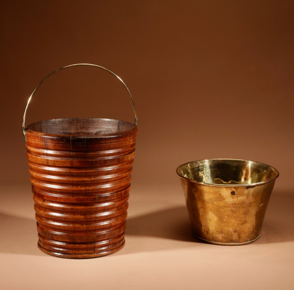 A tapered, coopered walnut bucket featuring horizontal ribbed bands, a fitted brass liner, and a brass swing handle. View VII