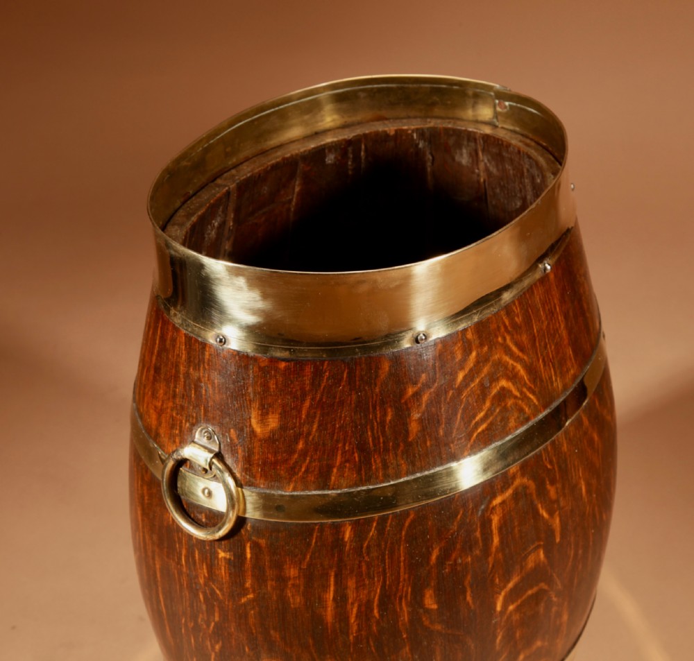 An oval coopered oak umbrella stand featuring polished brass binding straps and ring handles on the sides. View III