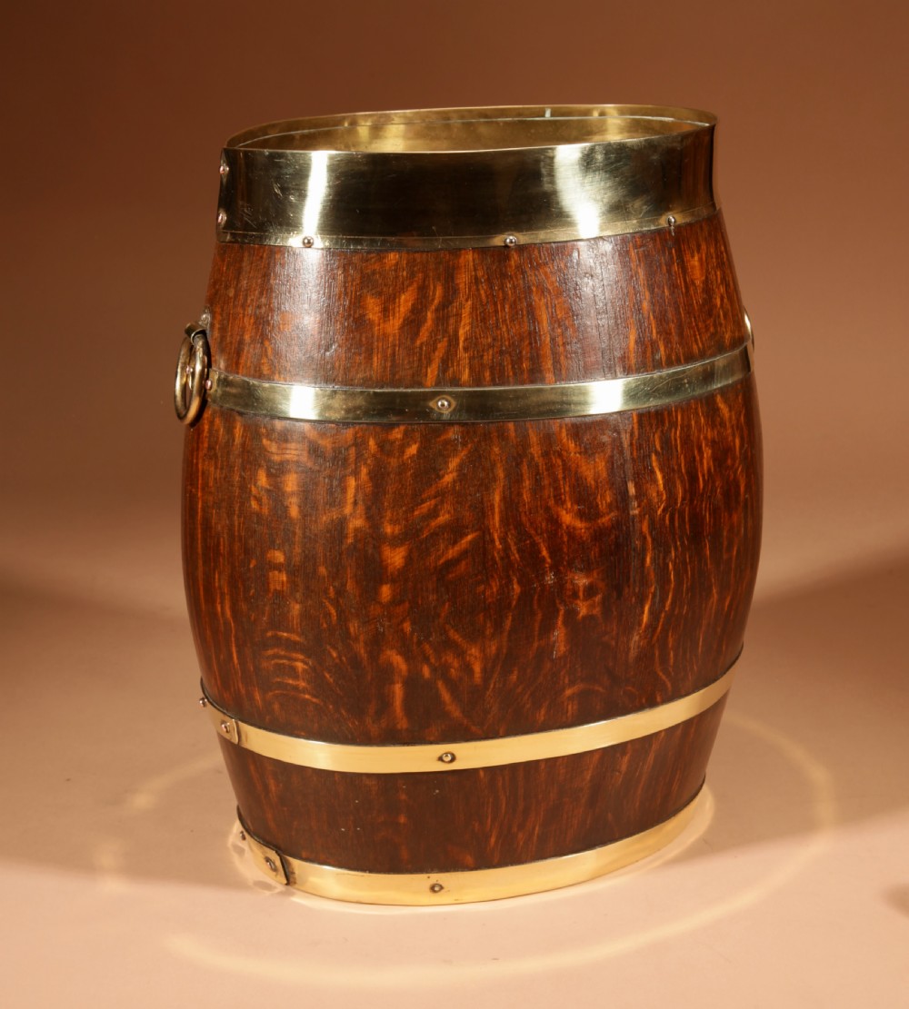 An oval coopered oak umbrella stand featuring polished brass binding straps and ring handles on the sides. View IV