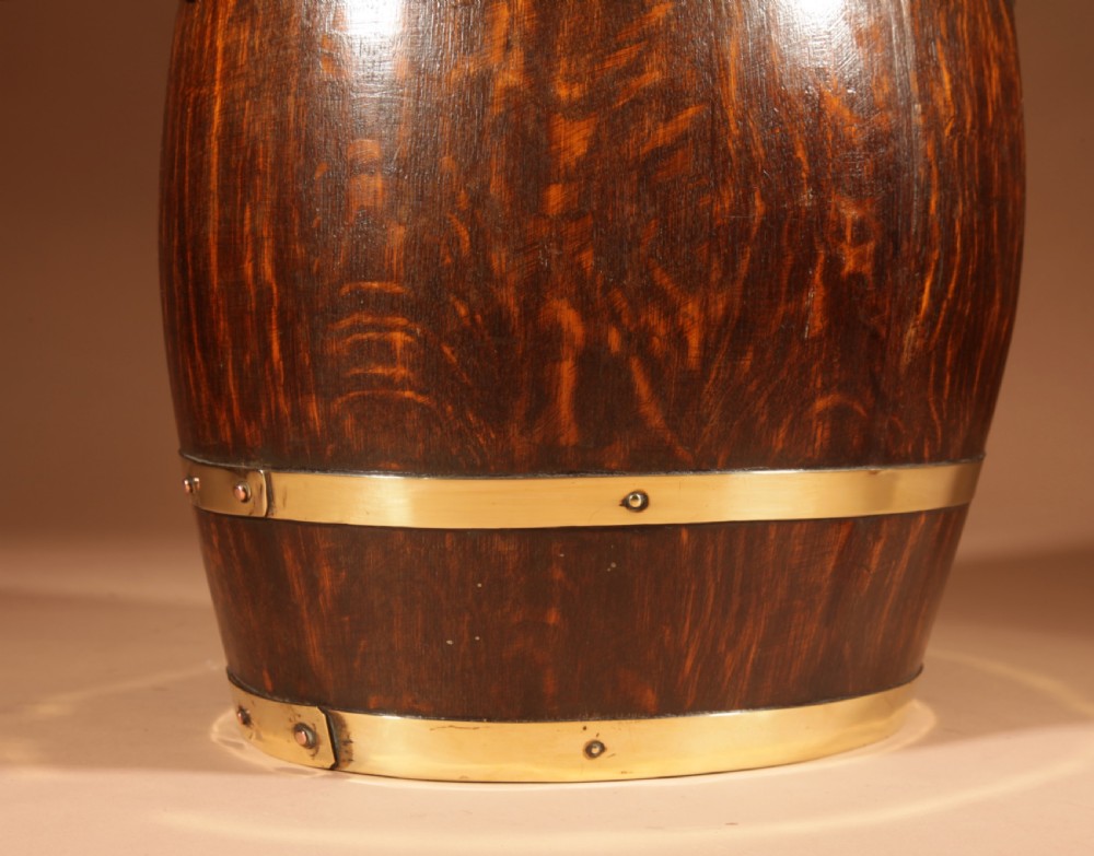 An oval coopered oak umbrella stand featuring polished brass binding straps and ring handles on the sides. View V
