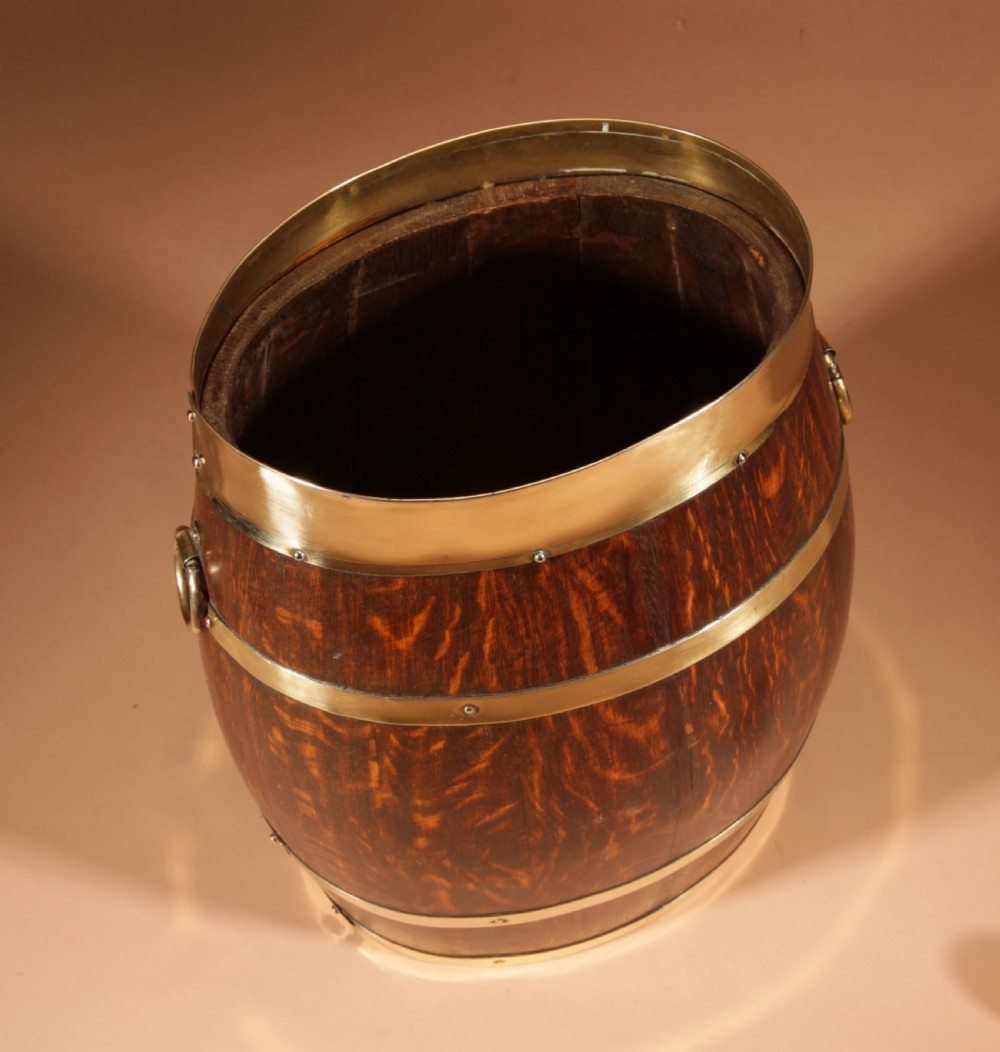 An oval coopered oak umbrella stand featuring polished brass binding straps and ring handles on the sides. View VI