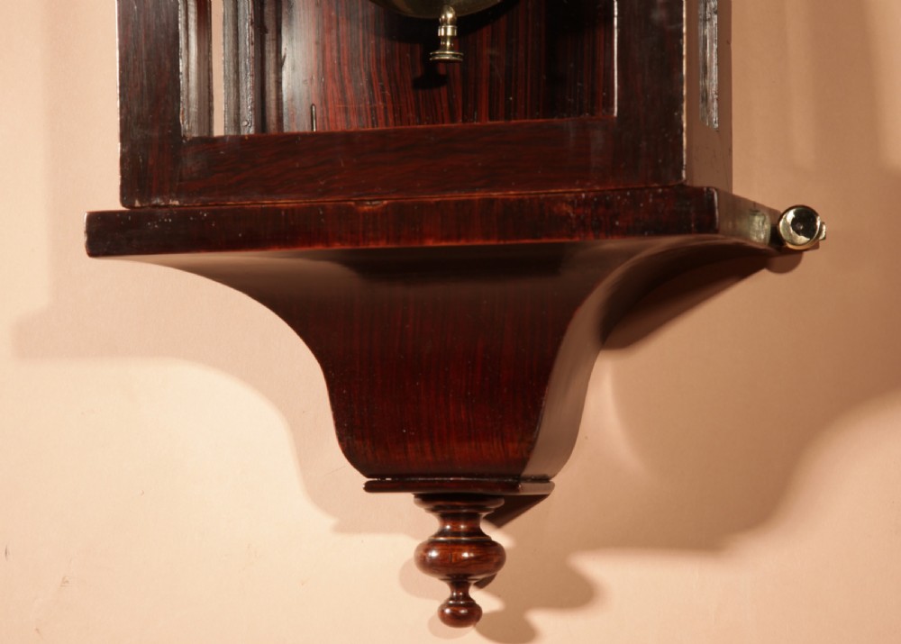A nineteenth-century Black Forest wall clock in the Vienna regulator style, featuring a dark rosewood case, white enamel dial, and brass pendulum. View V