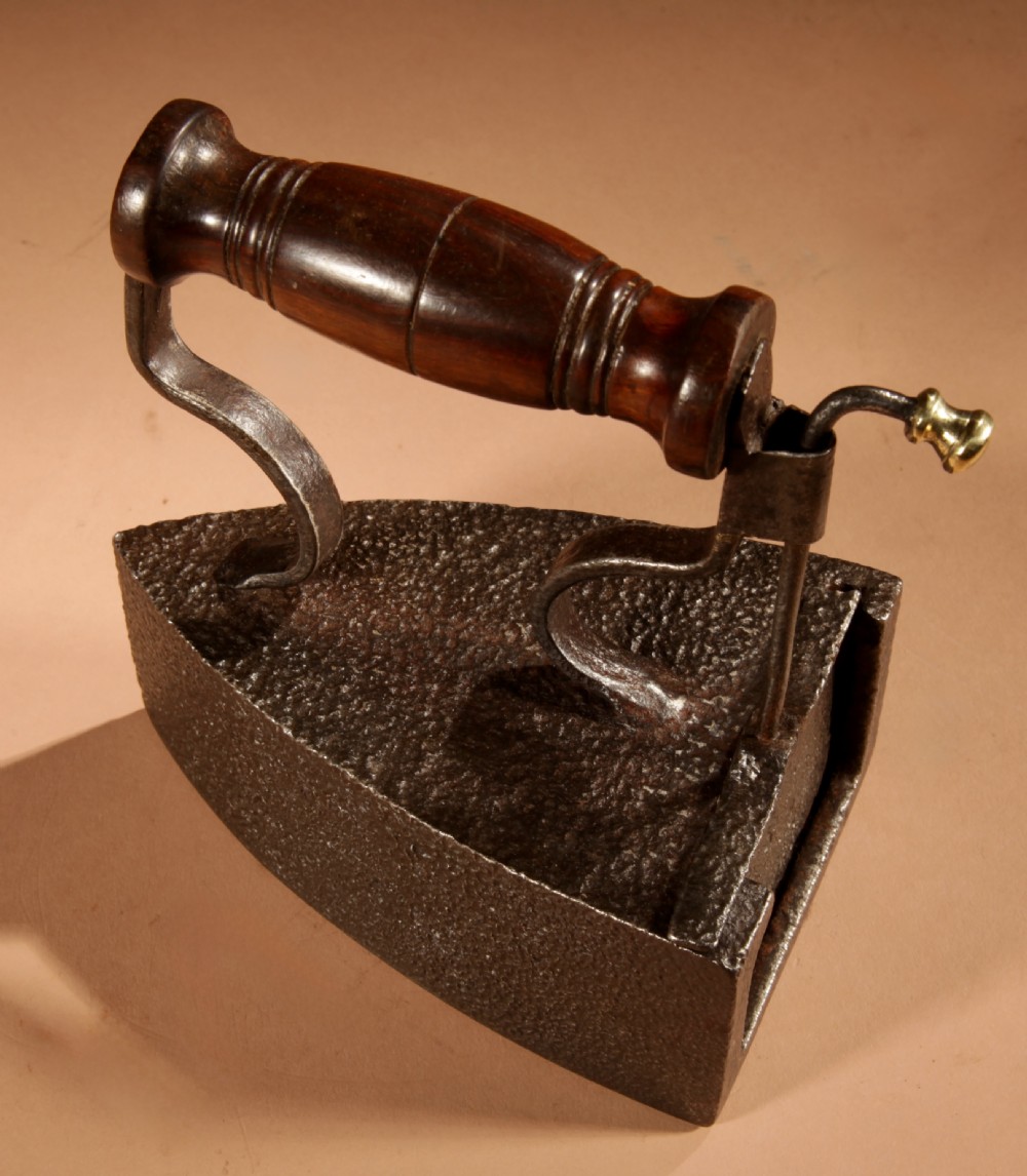 A Victorian cast iron box iron with a turned wooden handle, brass latch, and an accompanying iron slug on a plain background. View VIII